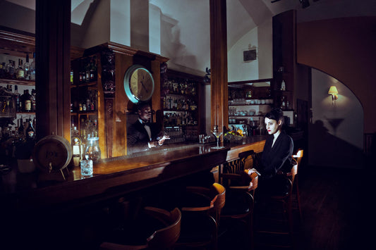 A lonely woman sitting in an empty bar with a glass of Martini.